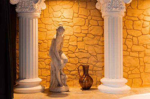 a statue of a woman standing between two white columns at La Suite de Vénus - Chambre à thème Love Room Jacuzzi et Pièce Secrète - Évasion pour deux in Schirrhein
