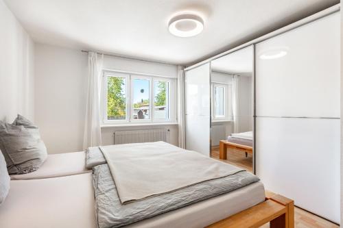 a white bedroom with a bed and a window at K8 Living in Wehr