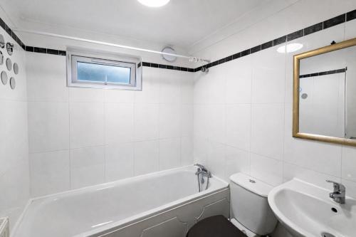 a white bathroom with a tub and a sink at Cosy City Hideout in London