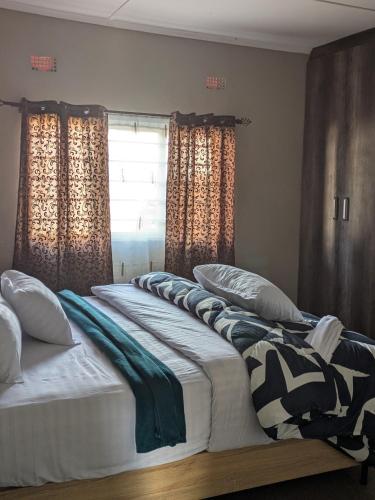 two twin beds in a bedroom with a window at Maneya Apartments in Kabwe