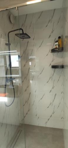 a glass shower in a bathroom with a marble wall at Ocean and Mountain View T2 N-3 in Lazareto