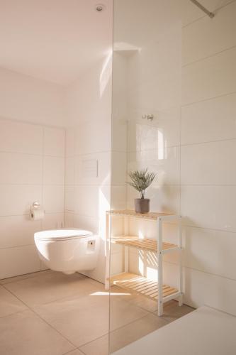 a white bathroom with a toilet and a sink at Landhotel Strandallee in Wunstorf
