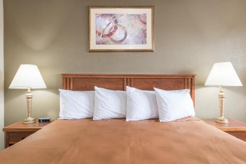 a bedroom with a bed with white pillows and two lamps at Red Carpet Inn Lancaster in Lancaster