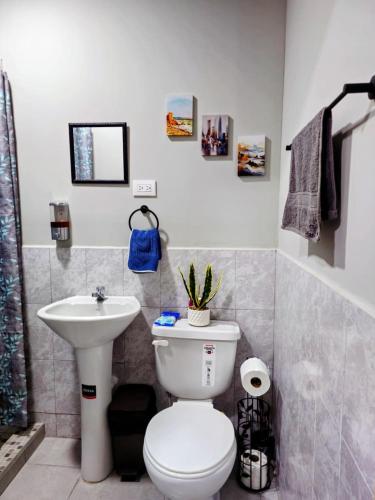 a bathroom with a white toilet and a sink at Quincho's Place in Santa Ana