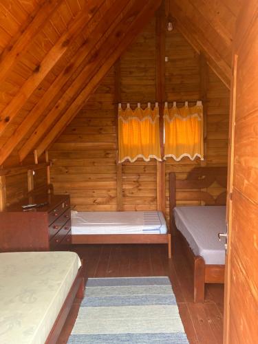 a bedroom with two beds in a wooden cabin at Chalé do Carlos in Ibiúna