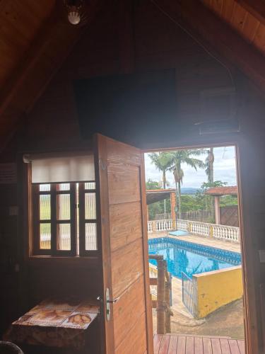 a door leading into a room with a swimming pool at Chalé do Carlos in Ibiúna