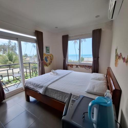 a bedroom with a bed and a view of the ocean at Aloha Hotel Mũi Né in Ấp Thiện Sơn