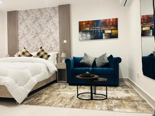 a bedroom with a bed and a blue couch at AccraAura-Airport Residential in Accra