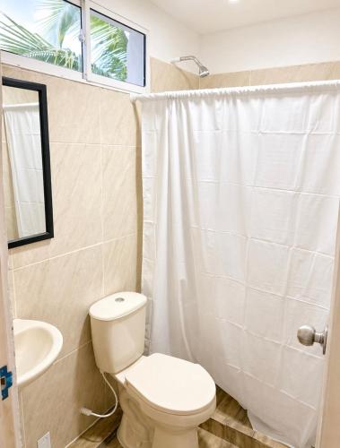 a white bathroom with a toilet and a sink at Hotel Playarena in Coveñas