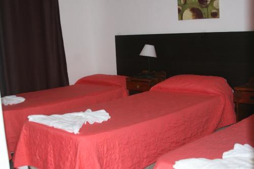 3 camas en una habitación de hotel con sábanas rojas en Palmas del Lago en Villa Carlos Paz
