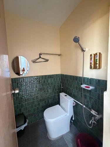 a bathroom with a toilet and a mirror and green tiles at Amad's Rental Space Family Room in Bantayan Island