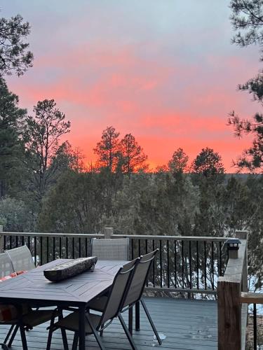 a table and chairs on a deck with a sunset at Blue Betty Acre in Overgaard