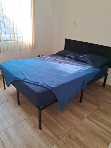a bed in a room with a blue blanket on it at Pousada Paula Lima II in Juiz de Fora