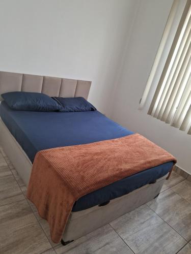 a bedroom with a bed with a blue blanket on it at Pousada Paula Lima II in Juiz de Fora