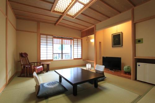a living room with a table and a tv at 温泉旅館 湯さか荘 in Hakone