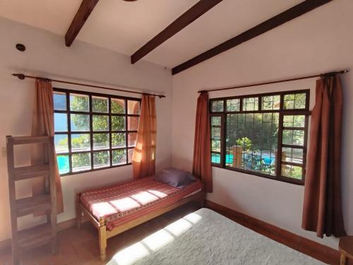 a bedroom with a bed and two windows at El Cafetal in Coroico