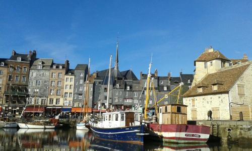 a group of boats docked in a harbor with buildings at La Cabane du Pecheur in Honfleur