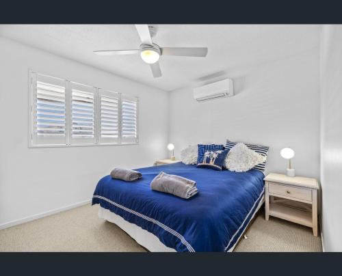 a bedroom with a blue bed and a ceiling fan at Walk to Beach • Luxury Waterfront Penthouse in Mooloolaba