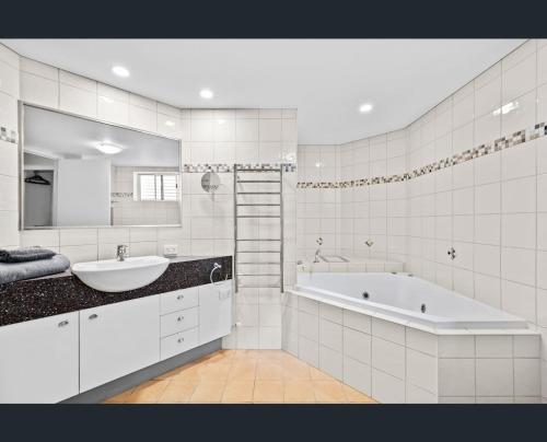 a white bathroom with a tub and a sink at Walk to Beach • Luxury Waterfront Penthouse in Mooloolaba