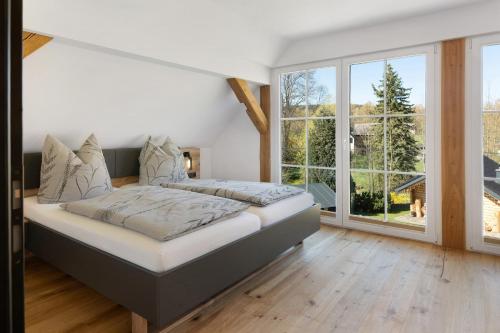 a bedroom with a bed and a large window at Vogtlandstadl - Vogtland Chalet in Bad Brambach