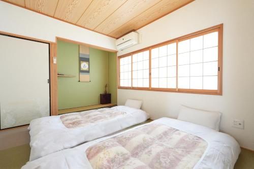 two beds in a room with a window at 嵐lan in Kyoto