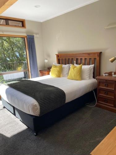 a bedroom with a large bed with yellow pillows at Pukawa Villas Formerly Oreti Village Resort in Kuratau