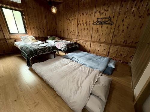two beds in a room with wooden walls at Retreat 舞月 in Tanabe