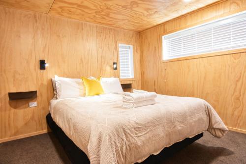 a bedroom with a bed with wooden walls and a window at Serene Star in Lake Tekapo