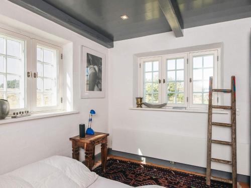 a bedroom with white walls and windows and a ladder at Home with Spa and Fireplace in Fanø