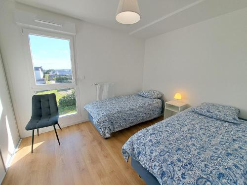 a bedroom with two beds and a chair and a window at Sea View Family Stay in Plouarzel in Plouarzel
