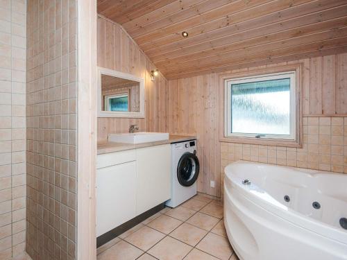 a bathroom with a tub sink and a washing machine at 8 person holiday home in Tarm in Tarm
