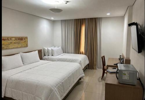 a hotel room with two beds and a desk at Flat hotel Blue tree no adrianopolis Até 4 pessoas in Manaus