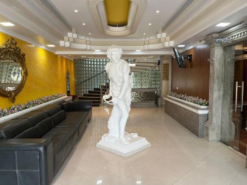 a statue in a lobby with a couch and stairs at Hotel Troya in Ibarra