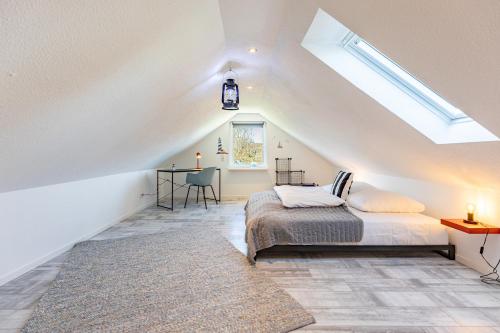 a attic bedroom with a bed and a desk at Cottage am Deich Whg Mareile in Uelvesbüll