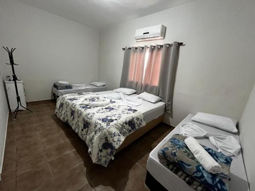 a small room with two beds and a window at Casa Vitória in Aparecida