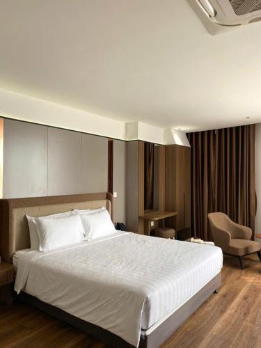 a bedroom with a large white bed and a chair at ASEAN MINH NGUYỆT Hotel in Nhân Mỹ