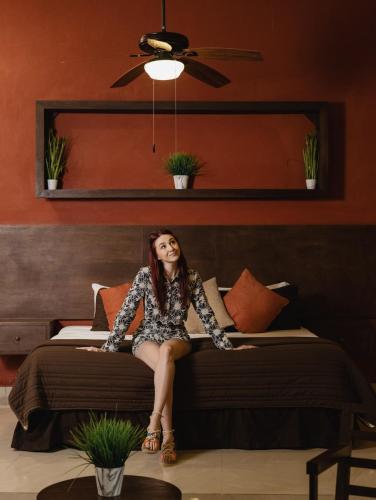 Eine Frau sitzt auf einem Bett in der Unterkunft Hotel Rinconada del Convento - Izamal in Izamal