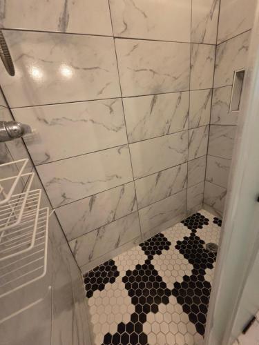 a bathroom with a shower with a black and white tile floor at Executive private room in Irvington