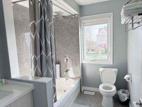 a bathroom with a toilet and a tub and a window at Spacious New 3BR Townhome Walking to Falls in Niagara Falls