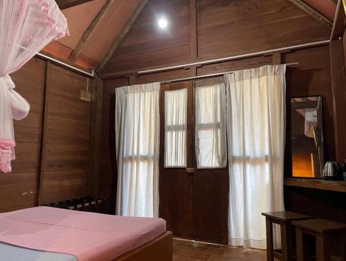a bedroom with a bed and a window with curtains at Cool Banyan Cabana in Trincomalee