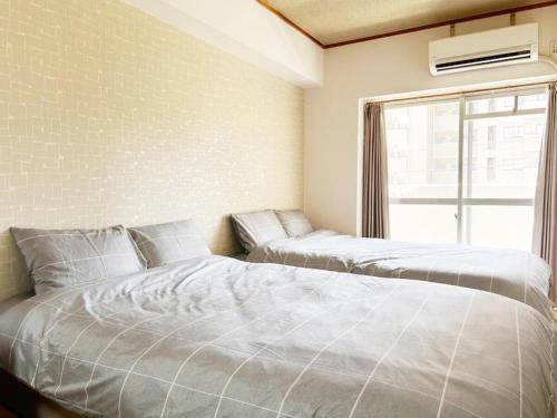 a bedroom with two beds and a window at Crest YS chiyoda 4B in Aoichō