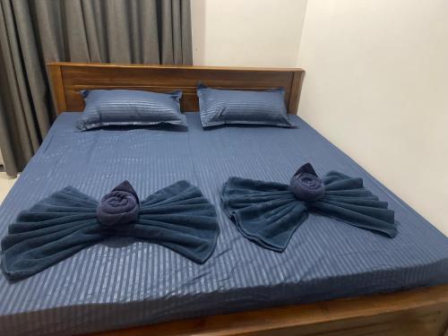 a bed with blue sheets with bow ties on it at The Yarl Home in Jaffna