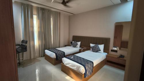 a hotel room with two beds and a window at Raja Krishna Mahal in Kushinagar