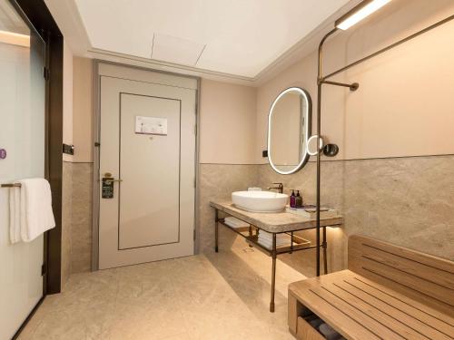 a bathroom with a sink and a mirror at Mercure Danzhou Yangpu Seaview in Dongshan
