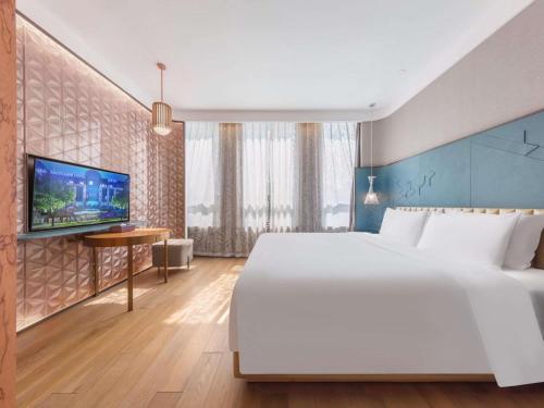 a bedroom with a large white bed and a tv at Mercure Beijing Dongzhimen in Beijing