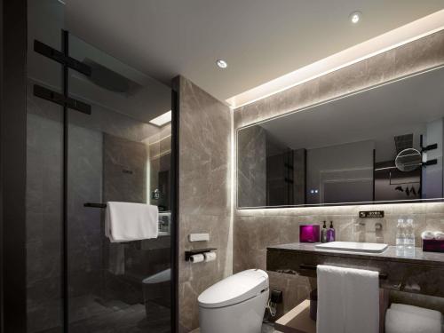 a bathroom with a toilet and a sink and a mirror at Mercure Guilin Yangshuo Xingping in Guilin