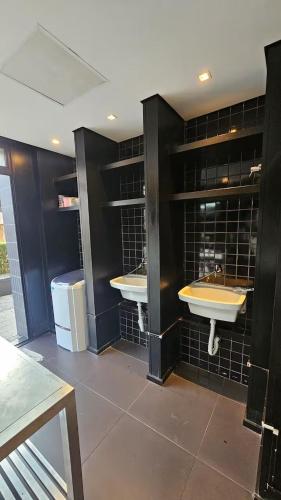 a bathroom with two sinks and black tiled walls at Studio Aurora, Bom Retiro - Anhembi - Com garagem in São Paulo
