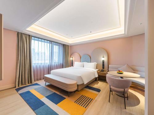 a bedroom with a bed and a desk and a table at Mercure Qingdao May Fourth Square in Qingdao