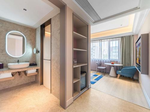 a bathroom with a sink and a mirror at Mercure Qingdao May Fourth Square in Qingdao