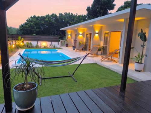 a hammock in front of a house with a pool at Shiraho Breeze Poolside Villa in Ishigaki Island